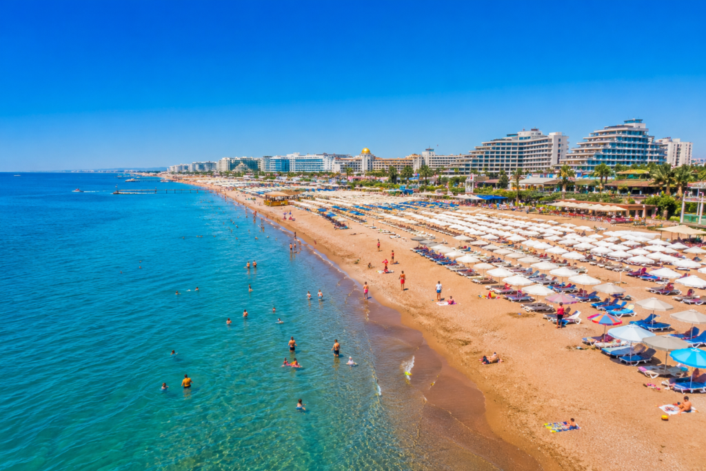 Lara Beach Antalya — golden sandy beach with turquoise Mediterranean sea, sunbeds and luxury resort hotels in the background