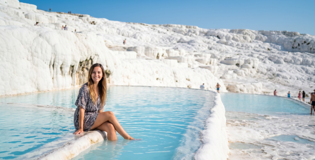 Young woman sitting in Pamukkale thermal pool white travertine terraces Turkey