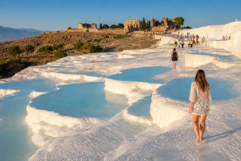 Pamukkale white travertine terraces with turquoise thermal pools and Hierapolis ruins in the background — day trip from Antalya