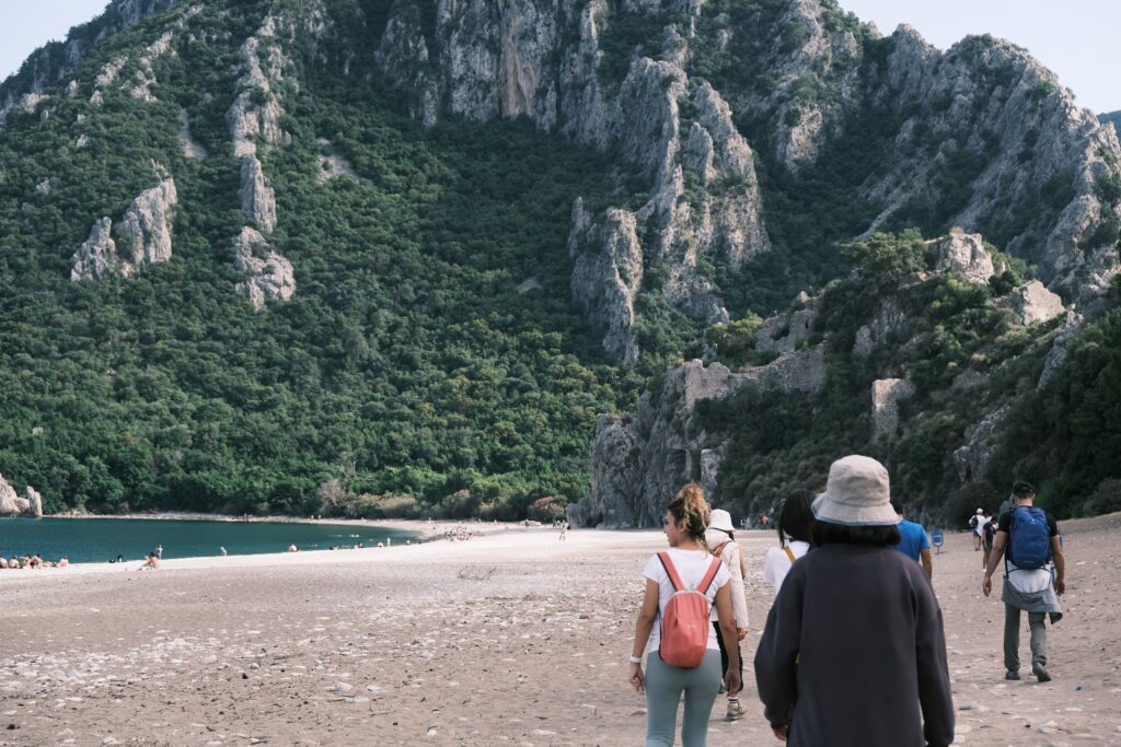 People walking along Cirali Beach with mountains in the background, Antalya
