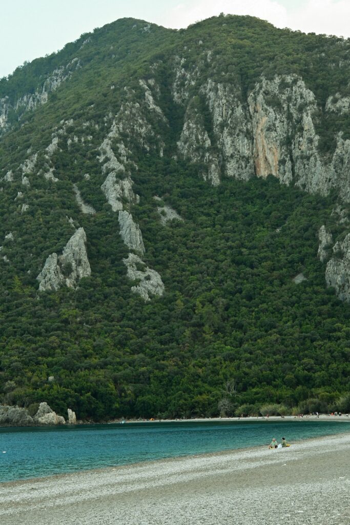 Serene pebble beach against a lush, rocky mountain in Cirali, Antalya