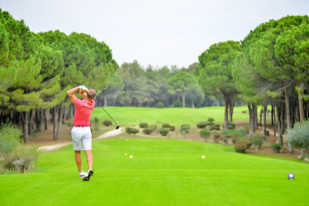Golfer swinging a club on a lush golf course in Belek, Antalya