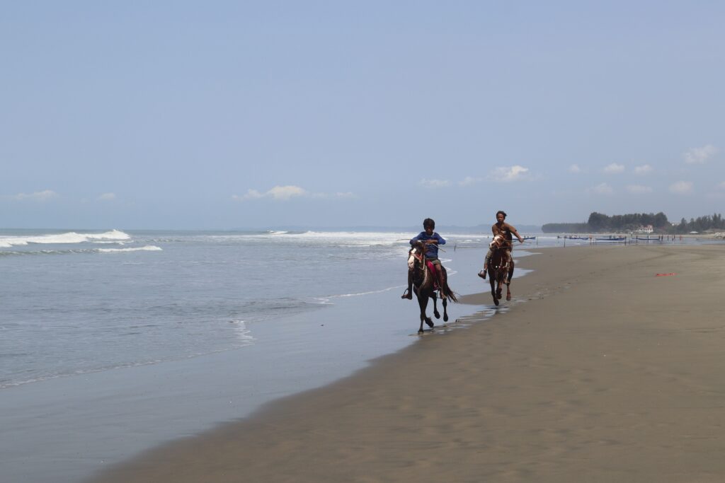 Two horse riders on a sandy beach in Antalya on a sunny day