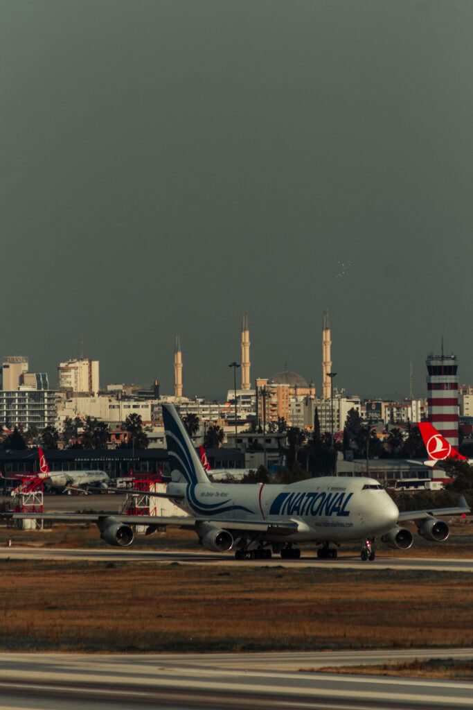Large airplane taxiing on a runway with a cityscape backdrop