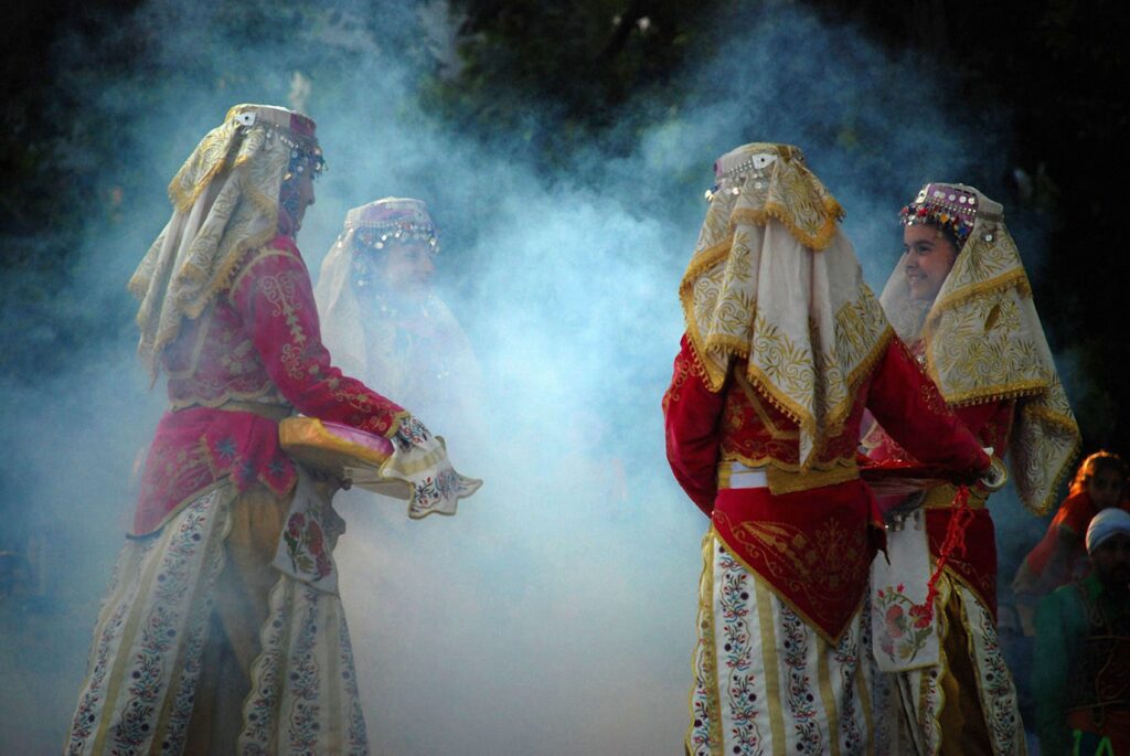 Performers in traditional Turkish attire on stage with smoke effects